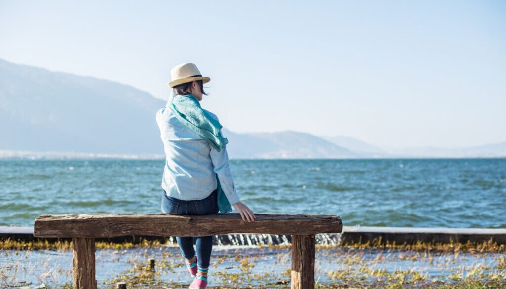 Rear view of peaceful woman sitting on a wooden bench