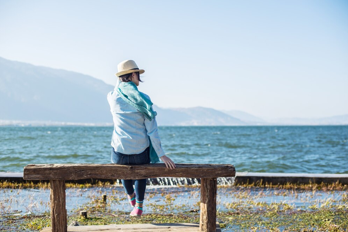 Rear view of peaceful woman sitting on a wooden bench